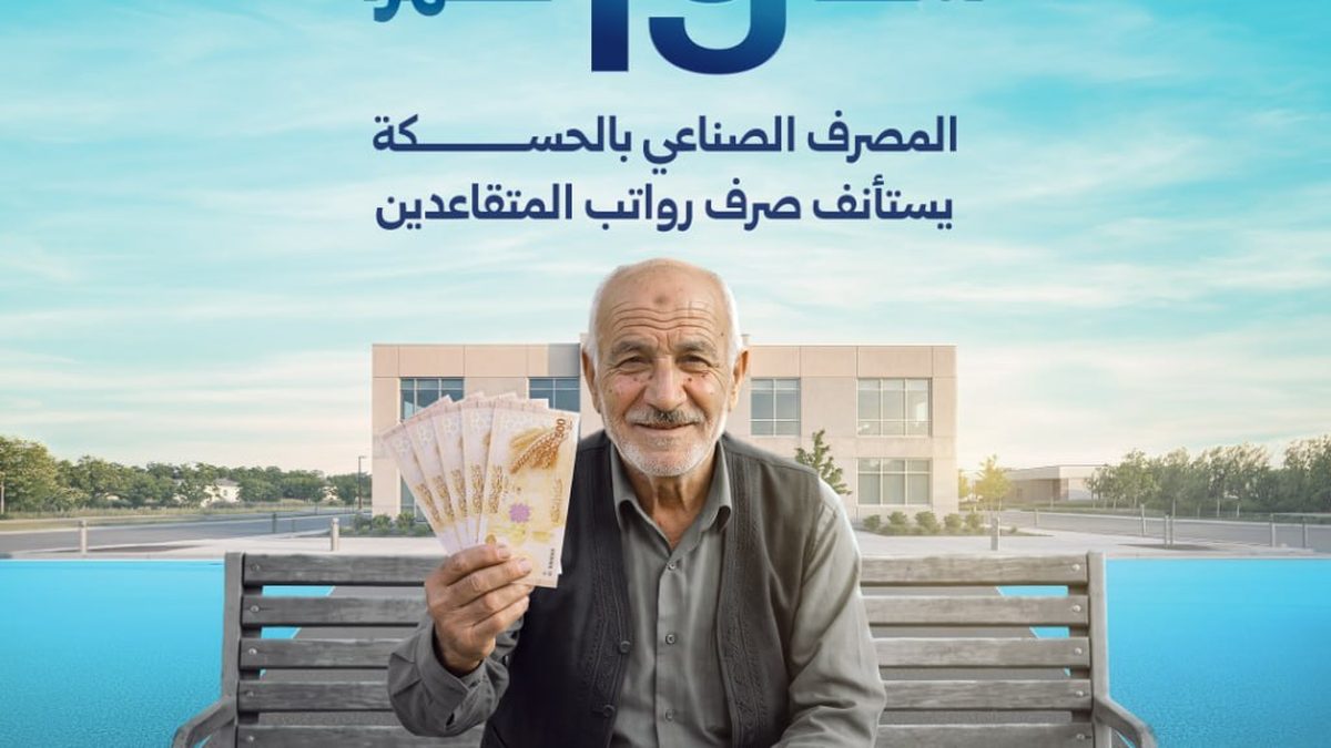 A bank teller hands documents to a retiree at the Industrial Bank counter in Hasakah
